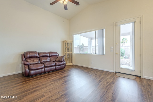 living room with dark wood finished floors, vaulted ceiling, baseboards, and a wealth of natural light