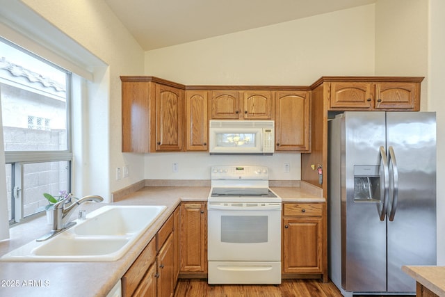 kitchen with white appliances, vaulted ceiling, light countertops, and a sink