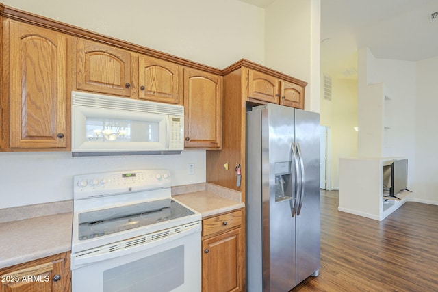 kitchen with white appliances, dark wood-type flooring, brown cabinetry, and light countertops