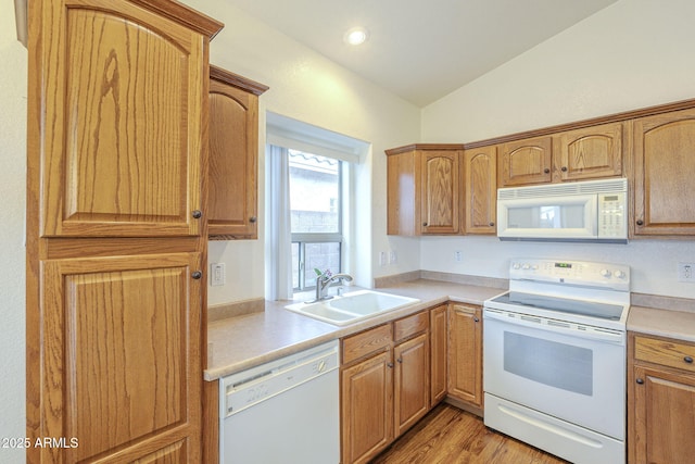 kitchen featuring white appliances, lofted ceiling, light wood-style flooring, a sink, and light countertops