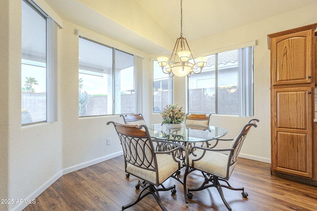 dining space with dark wood-style floors, a notable chandelier, baseboards, and vaulted ceiling