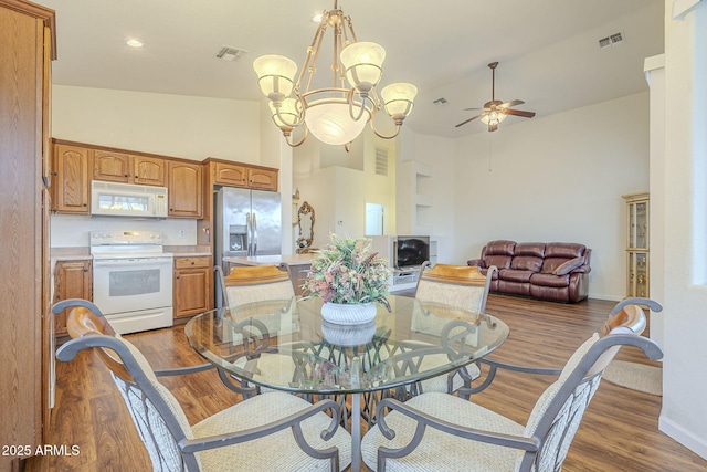 dining space featuring visible vents, baseboards, a high ceiling, and wood finished floors