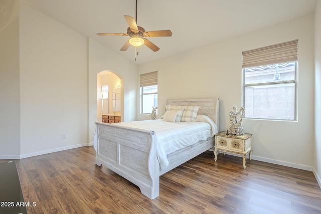 bedroom featuring baseboards, arched walkways, and wood finished floors