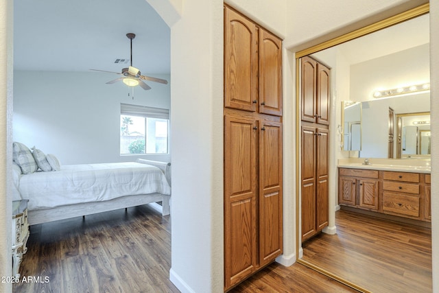 bedroom featuring visible vents, baseboards, dark wood finished floors, ensuite bathroom, and a ceiling fan