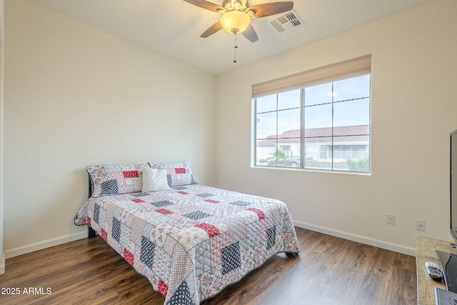 bedroom featuring ceiling fan, visible vents, baseboards, and wood finished floors