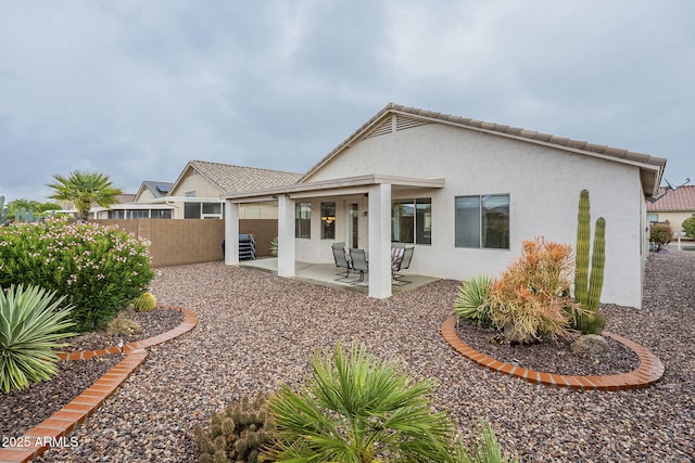 rear view of property with a patio area, stucco siding, and fence