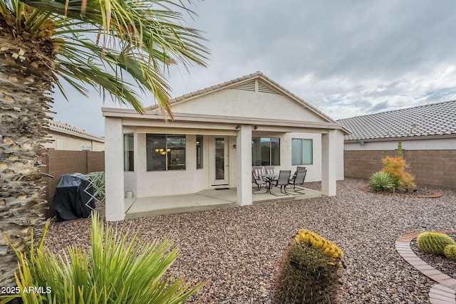 rear view of property featuring stucco siding, a fenced backyard, and a patio area