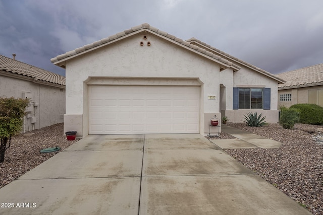 view of front of home featuring a tile roof, a garage, driveway, and stucco siding