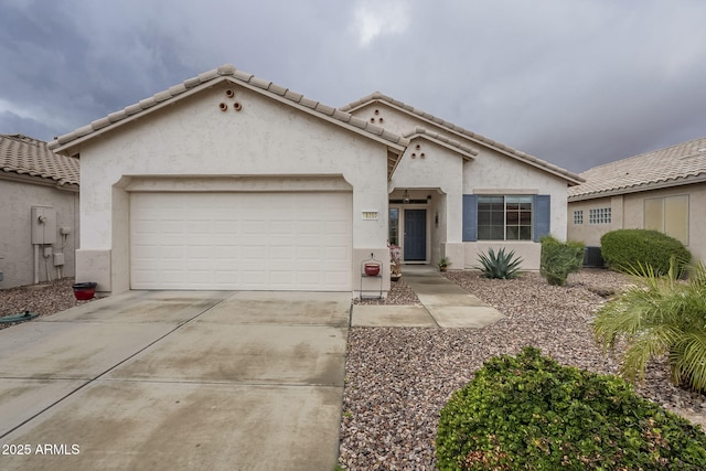 mediterranean / spanish house featuring concrete driveway, an attached garage, a tile roof, and stucco siding