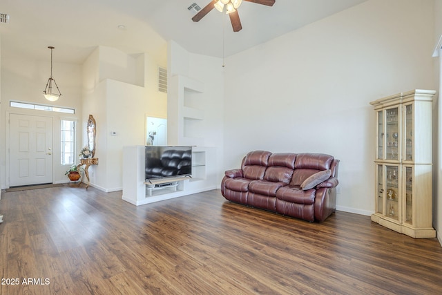 living area featuring visible vents, high vaulted ceiling, baseboards, and wood finished floors