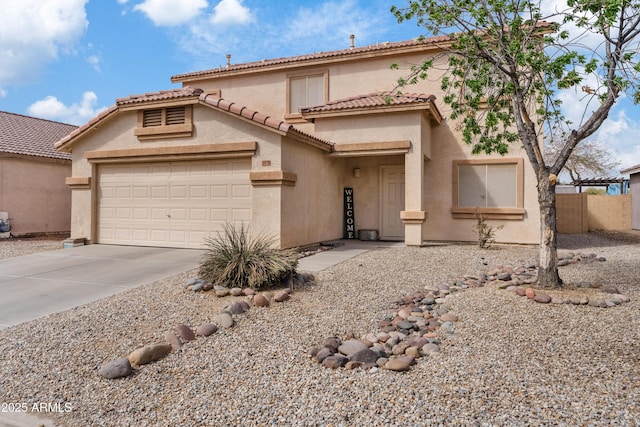 mediterranean / spanish home with stucco siding, an attached garage, concrete driveway, and fence