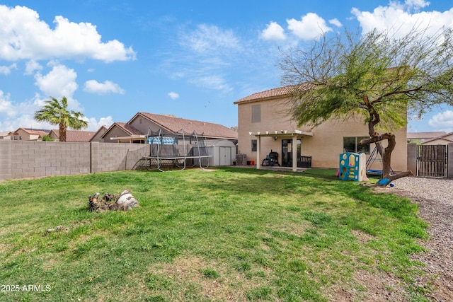 view of yard featuring a storage unit, an outbuilding, a trampoline, a fenced backyard, and a patio area