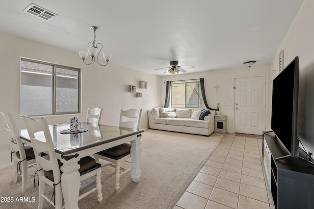 dining space featuring visible vents, light carpet, light tile patterned flooring, and ceiling fan with notable chandelier