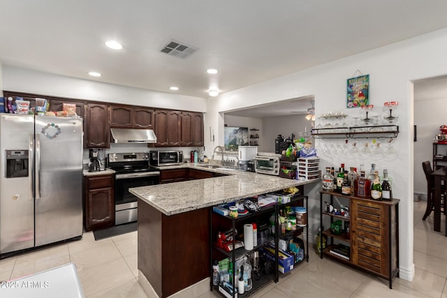 kitchen with sink, light stone counters, kitchen peninsula, stainless steel appliances, and dark brown cabinets