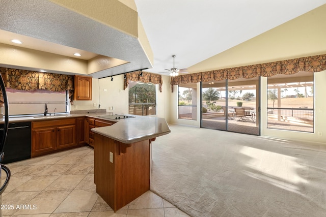 kitchen featuring sink, vaulted ceiling, light carpet, kitchen peninsula, and black appliances