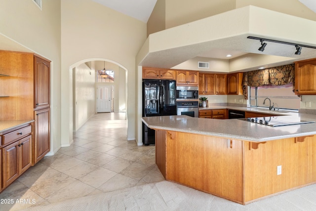 kitchen with a kitchen breakfast bar, kitchen peninsula, rail lighting, and black appliances