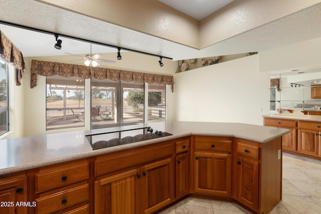 kitchen featuring ceiling fan, a textured ceiling, black electric cooktop, and kitchen peninsula