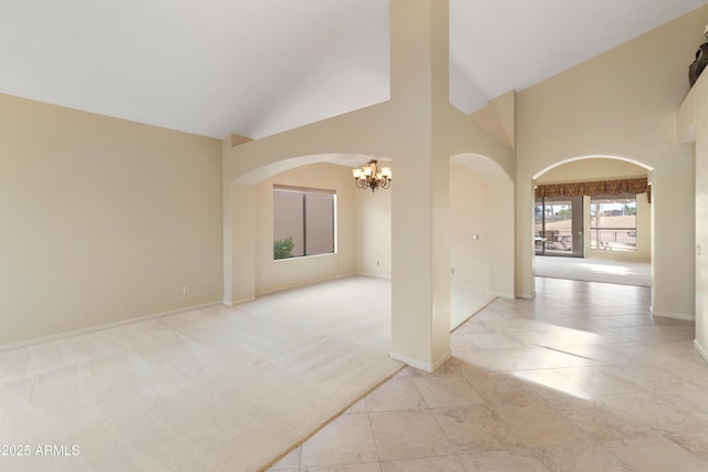 spare room featuring light colored carpet, a notable chandelier, and high vaulted ceiling