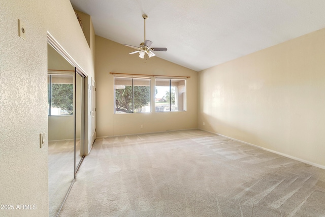 carpeted spare room with ceiling fan, vaulted ceiling, and a healthy amount of sunlight