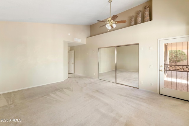 unfurnished bedroom featuring ceiling fan, a closet, high vaulted ceiling, and light carpet