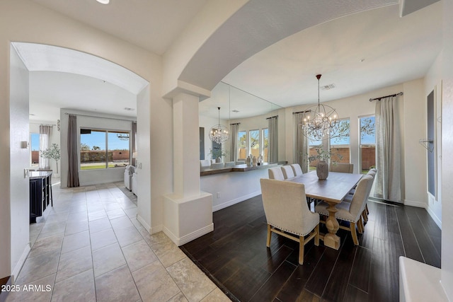 dining room featuring a notable chandelier, decorative columns, and light wood-type flooring