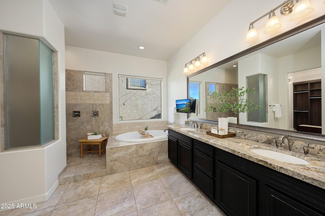 bathroom featuring vanity, tile patterned flooring, and tiled tub