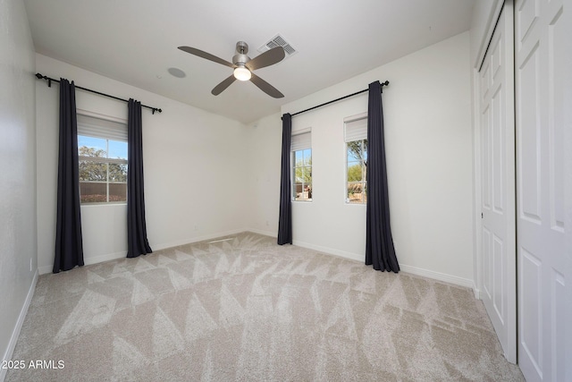 unfurnished bedroom featuring ceiling fan, a closet, and light carpet