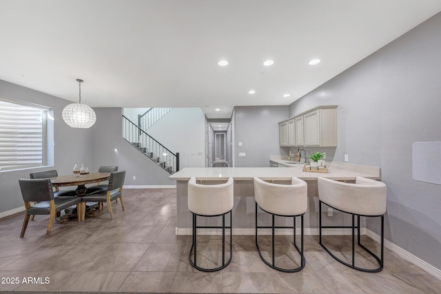 kitchen featuring sink, decorative light fixtures, kitchen peninsula, and a kitchen bar