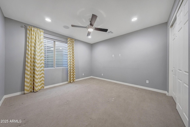 empty room featuring ceiling fan and light colored carpet