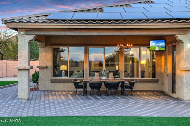 back house at dusk featuring a patio and solar panels