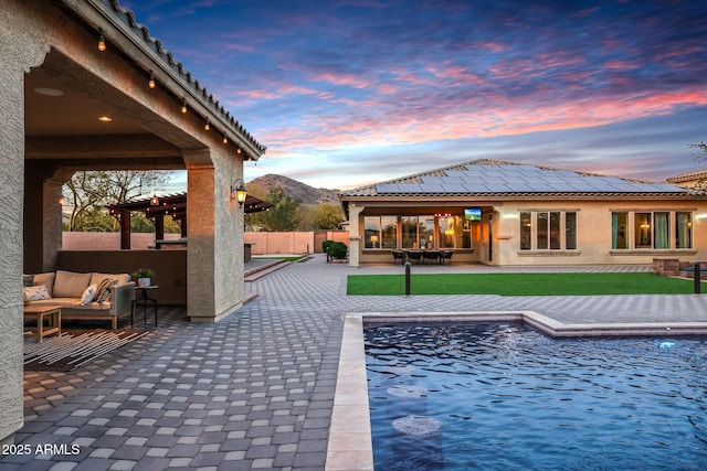 pool at dusk featuring an outdoor hangout area, a mountain view, and a patio area