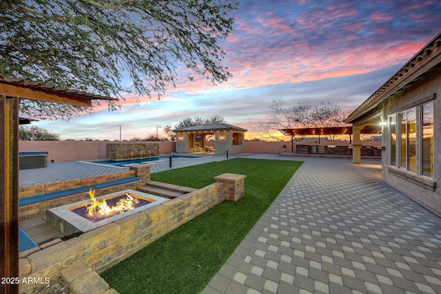 yard at dusk with an outdoor fire pit, an outdoor structure, a fenced in pool, and a patio area