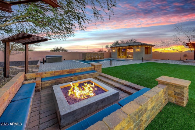 yard at dusk featuring a fenced in pool, a patio, an outbuilding, and an outdoor fire pit