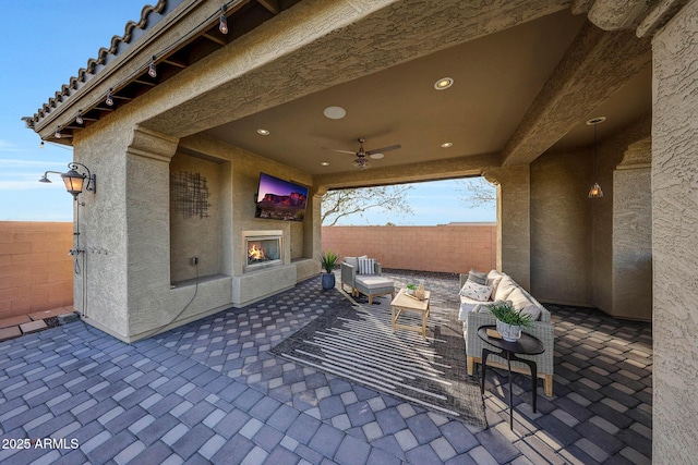 view of patio / terrace featuring ceiling fan and an outdoor living space with a fireplace