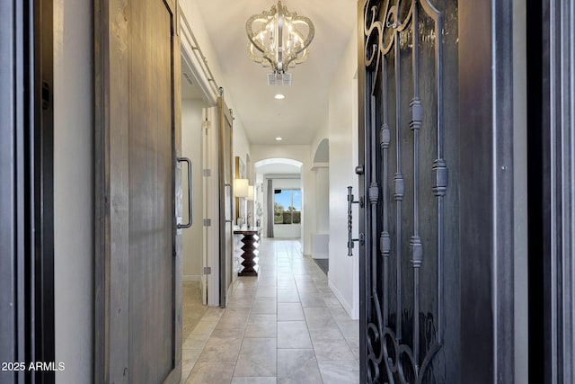 hallway featuring light tile patterned flooring and a chandelier