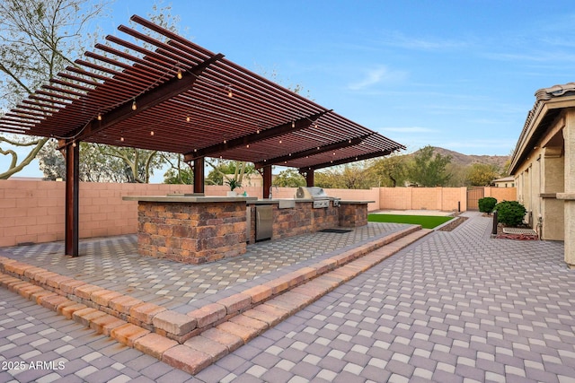 view of patio / terrace featuring exterior kitchen, a mountain view, and a pergola