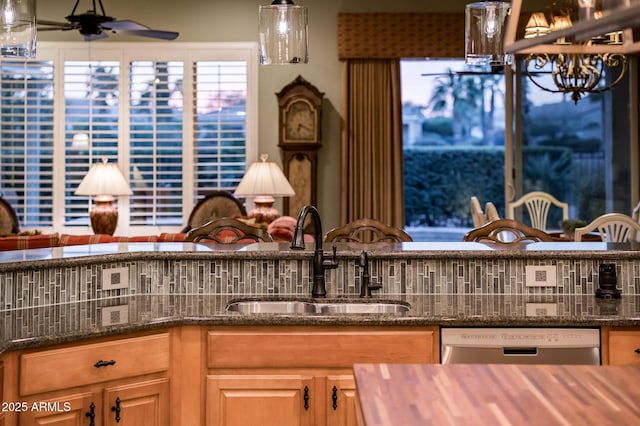 kitchen featuring a ceiling fan, dark stone counters, a sink, decorative backsplash, and dishwasher