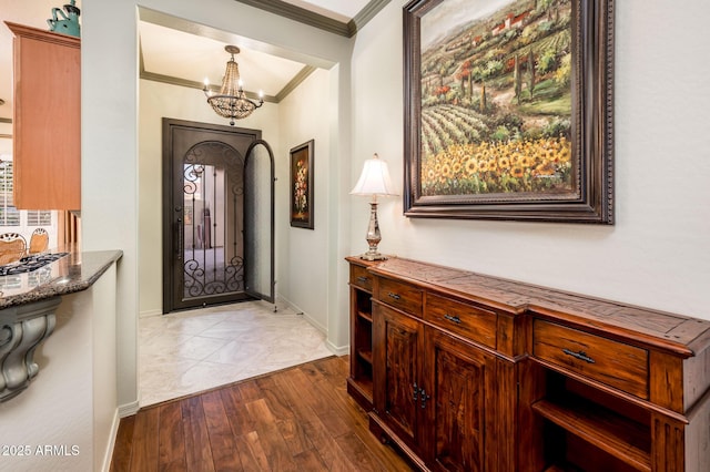 foyer featuring baseboards, an inviting chandelier, wood finished floors, and crown molding