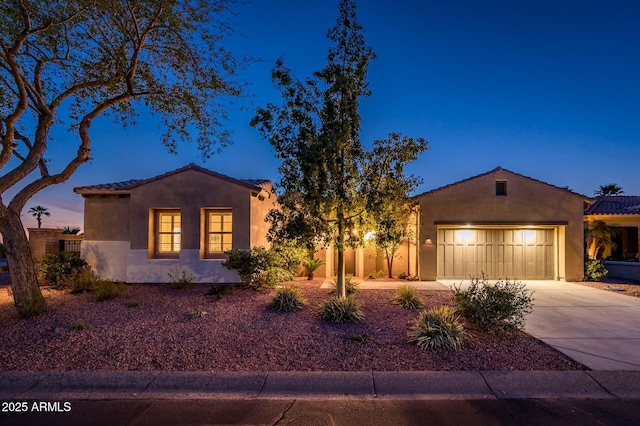 view of front of house with stucco siding, driveway, a tile roof, fence, and a garage