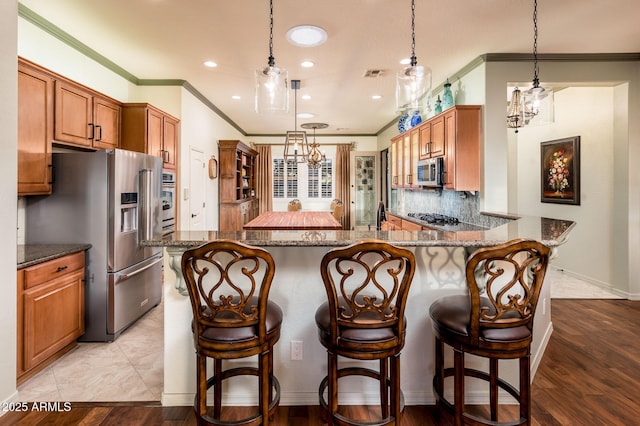 kitchen with dark stone countertops, stainless steel appliances, tasteful backsplash, and visible vents