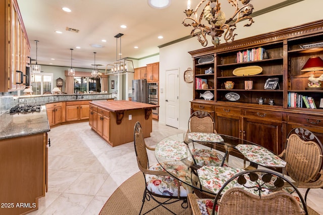 kitchen with visible vents, butcher block countertops, ornamental molding, a center island, and stainless steel appliances