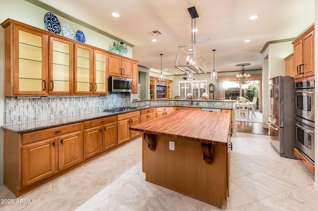 kitchen featuring visible vents, wooden counters, a kitchen island, a peninsula, and stainless steel appliances