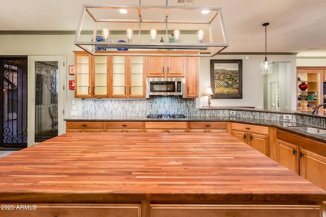 kitchen with a sink, stainless steel microwave, black gas stovetop, and butcher block counters