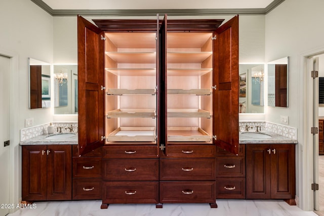 full bath featuring double vanity, ornamental molding, marble finish floor, and a sink