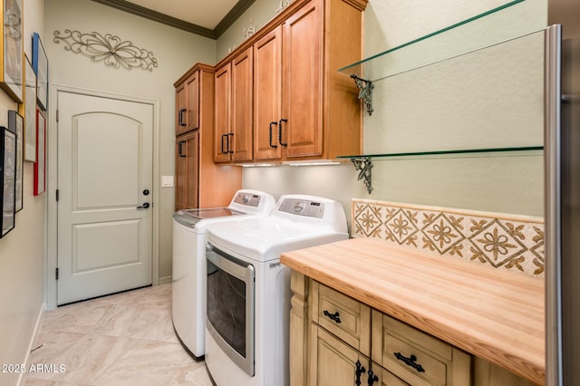 clothes washing area featuring ornamental molding, cabinet space, and washing machine and clothes dryer