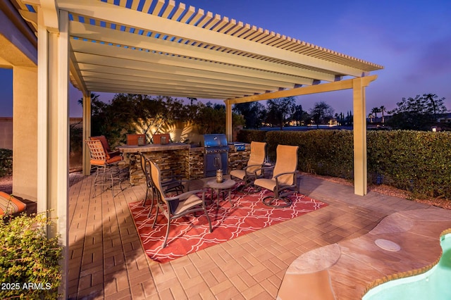 patio terrace at dusk with outdoor dining area, an outdoor kitchen, and a pergola