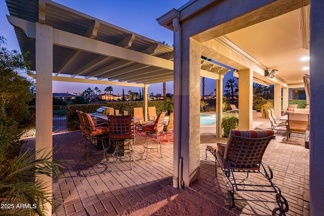 patio terrace at dusk with outdoor dining area, an outdoor pool, and a pergola