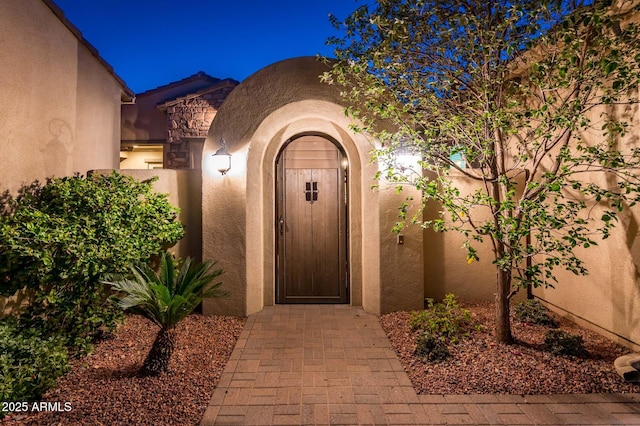 doorway to property featuring stucco siding and a gate