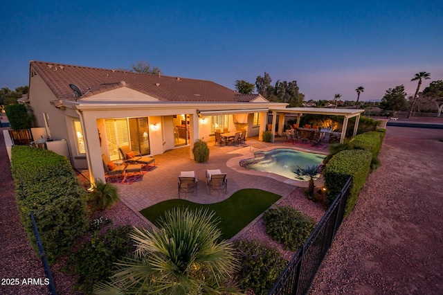 back of house at dusk with fence, outdoor dining area, an outdoor pool, stucco siding, and a patio area