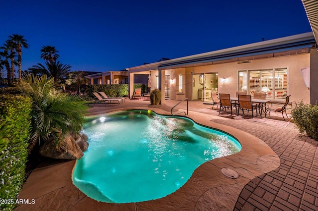 pool at night featuring an outdoor pool and a patio